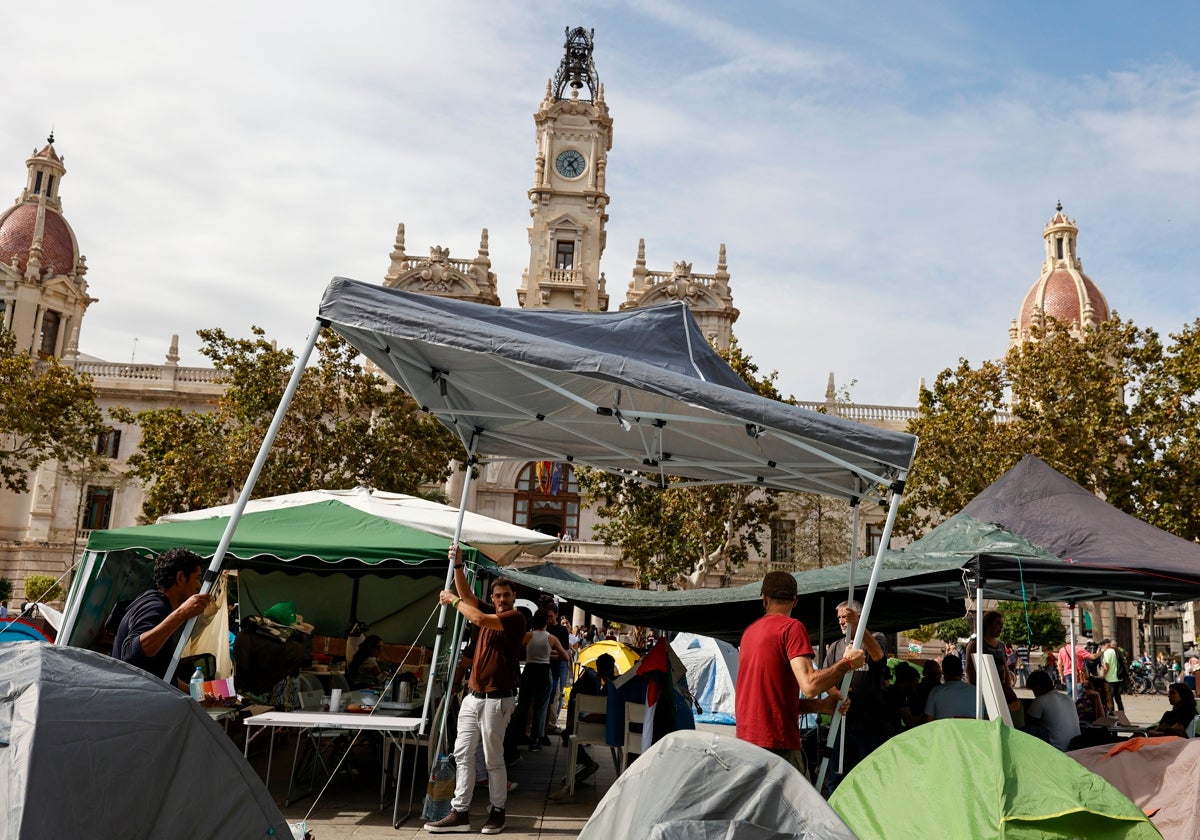 Los acampados colocan una carpa para resguardarse de la lluvia.