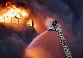 Un bombero ataca las llamas en el incendio de Campanar desde de la cesta de una autoescalera.