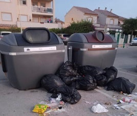 Bolsas de basura fuera de los contenedores.