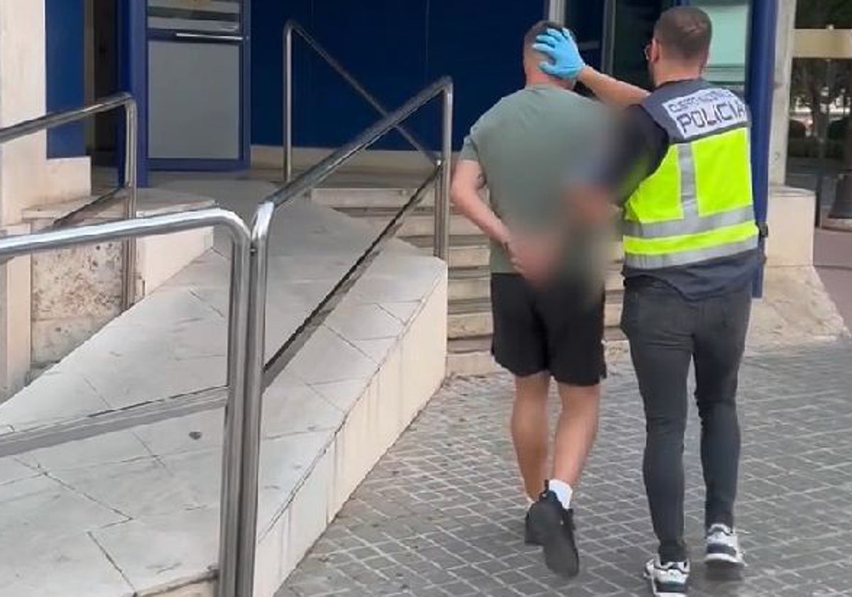 Un agente de la Policía Nacional traslada a uno de los presuntos estafadores hasta la Jefatura Superior de Valencia.