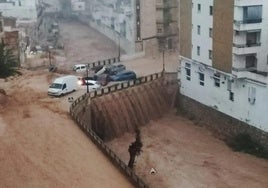 El barranco de Chiva desbordado a su paso por la población.