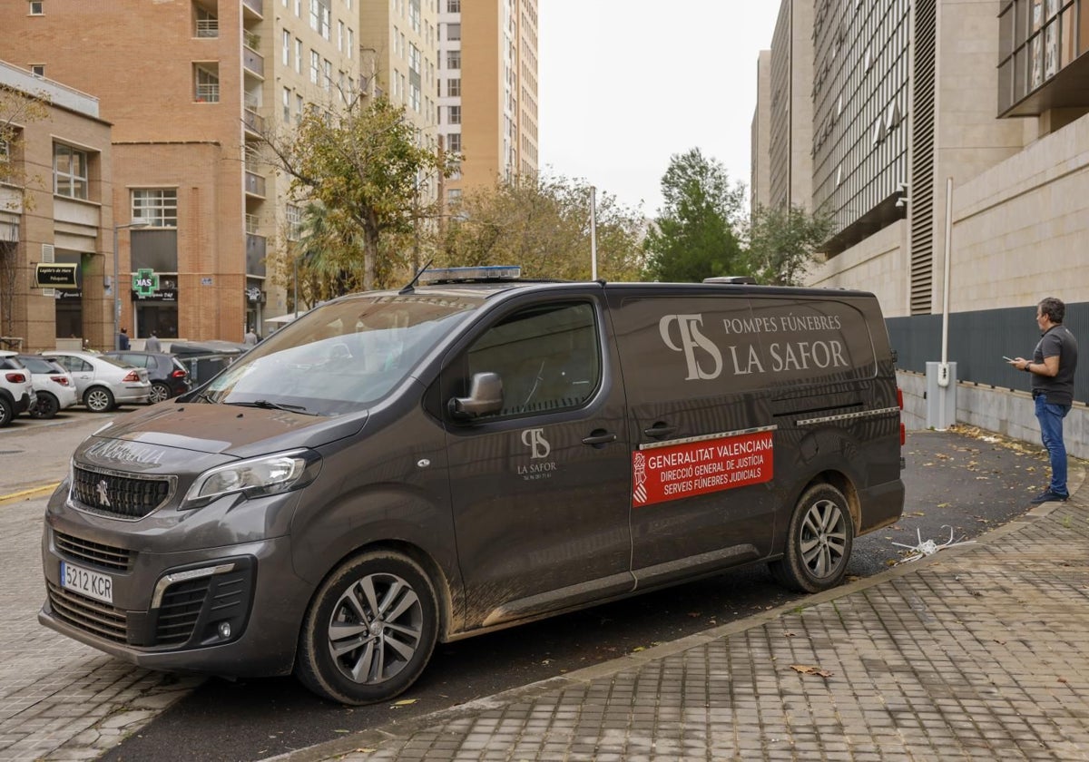 Una persona aguarda junto al vehículo del retén fúnebre estacionado en la Ciudad de la Justicia donde está el IML.