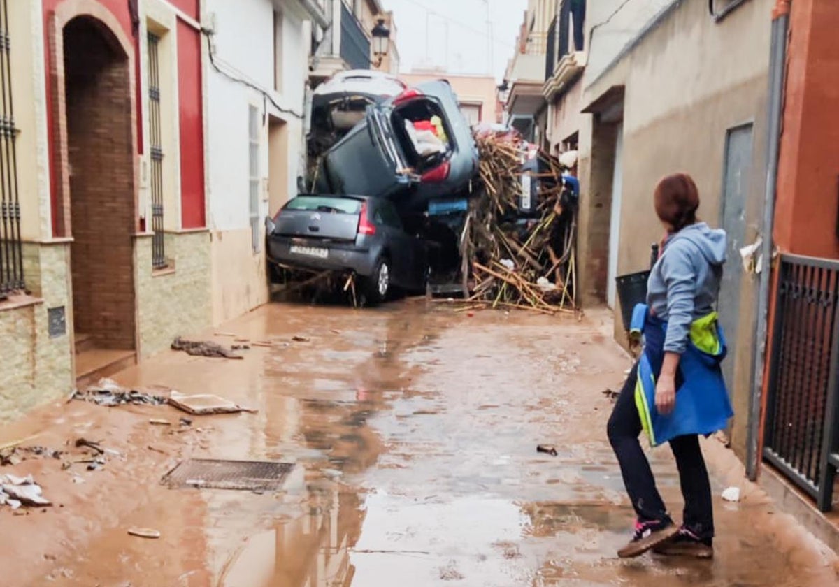 Una calle de Paiporta taponada por varios coches arrastrados por el agua.