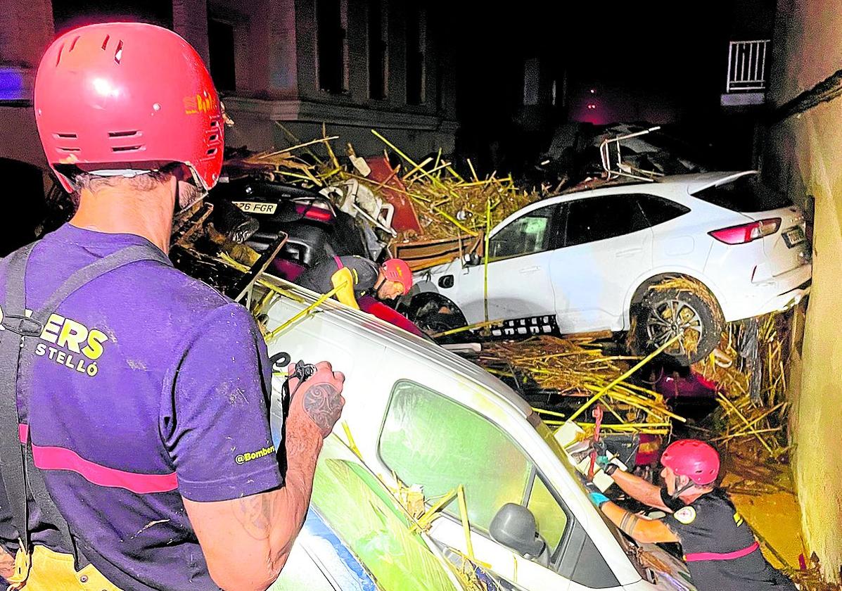 Dos bomberos juntoa a coches amontonados.