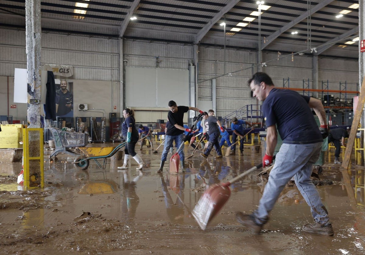 Trabajadores de una empresa de logística limpian el interior de una nave.