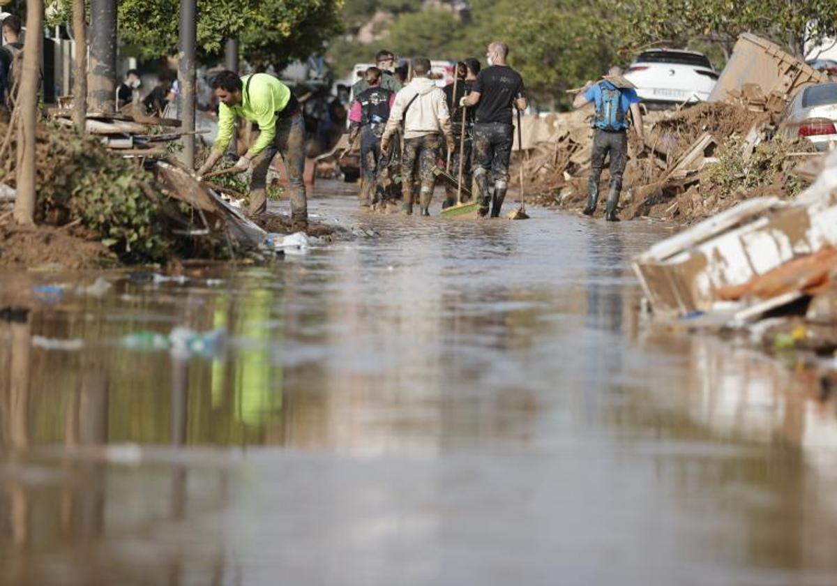 Voluntarios y vecinos trabajan en una calle de Paiporta tras el paso de la DANA.