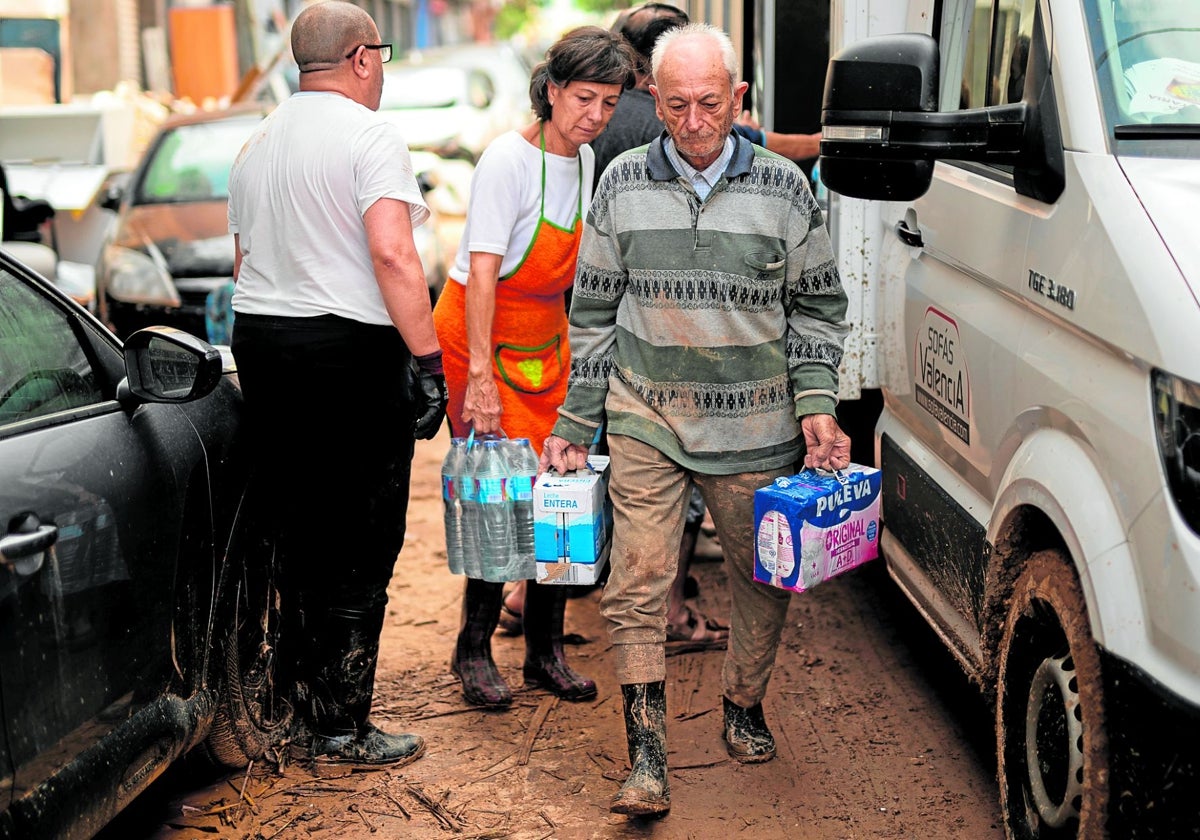 Un vecino de Algemesí recoge agua y leche de un camión con ayuda humanitaria.