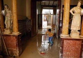 Juan, con la escoba, limpiando en casa de Purificación.