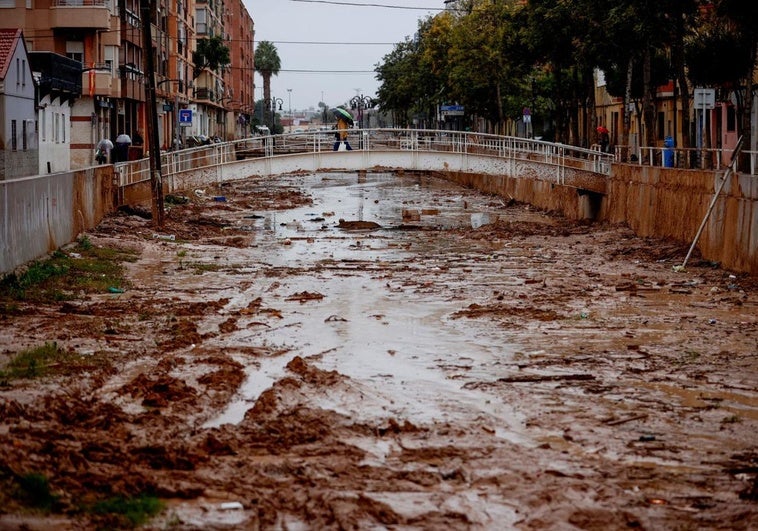 Una persona cruza el barranco de La Saleta que se desbordó recientemente debido a las fuertes lluvias en Aldaia.