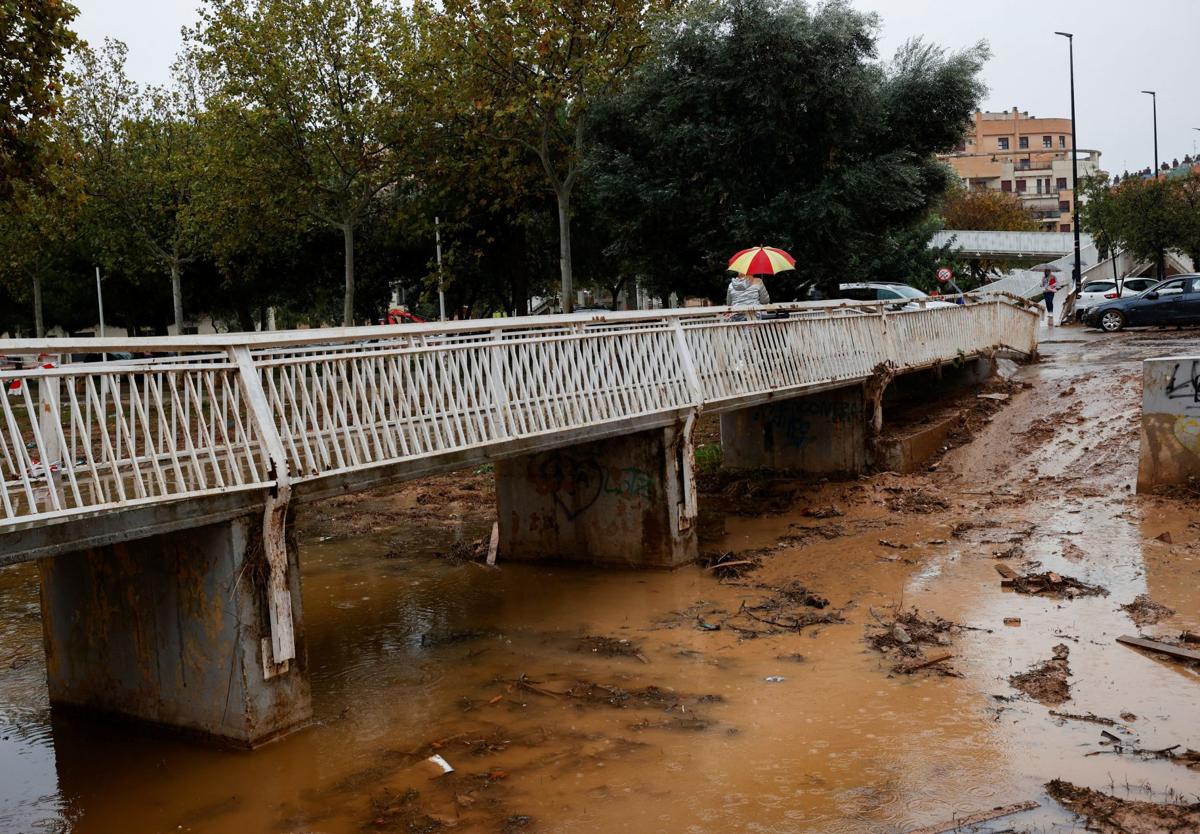 Una persona cruza el barranco de La Saleta desbordado recientemente por las fuertes lluvias en Aldaia.