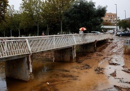 Una persona cruza el barranco de La Saleta desbordado recientemente por las fuertes lluvias en Aldaia.