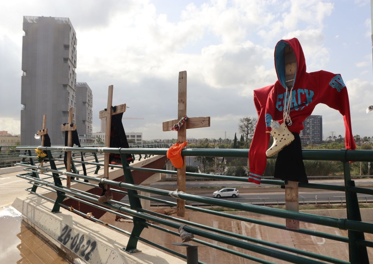 Imagen secundaria 1 - Cruces decoradas con ropa, botas y un peluche, en la pasarela que salva el río Turia.