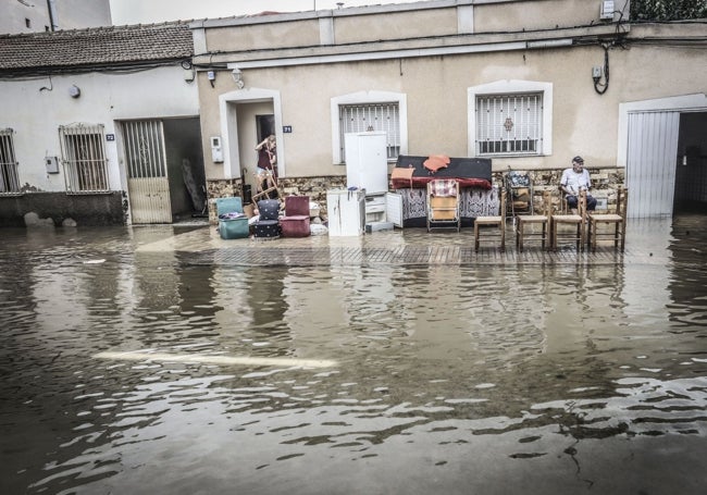 Un señor, sentado, contemplando las inundadas calles de Orihuela.