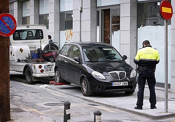 Un policía multa un coche mal estacionado en Valencia, imagen de archivo.