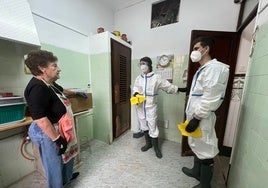 María Enrique, con dos voluntarios, en su casa tras recibir un microondas y vitro.