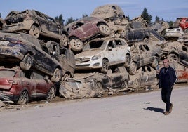 Un hombre pasa ante los innumerables coches apilados en Catarroja, tres semanas después de la DANA.