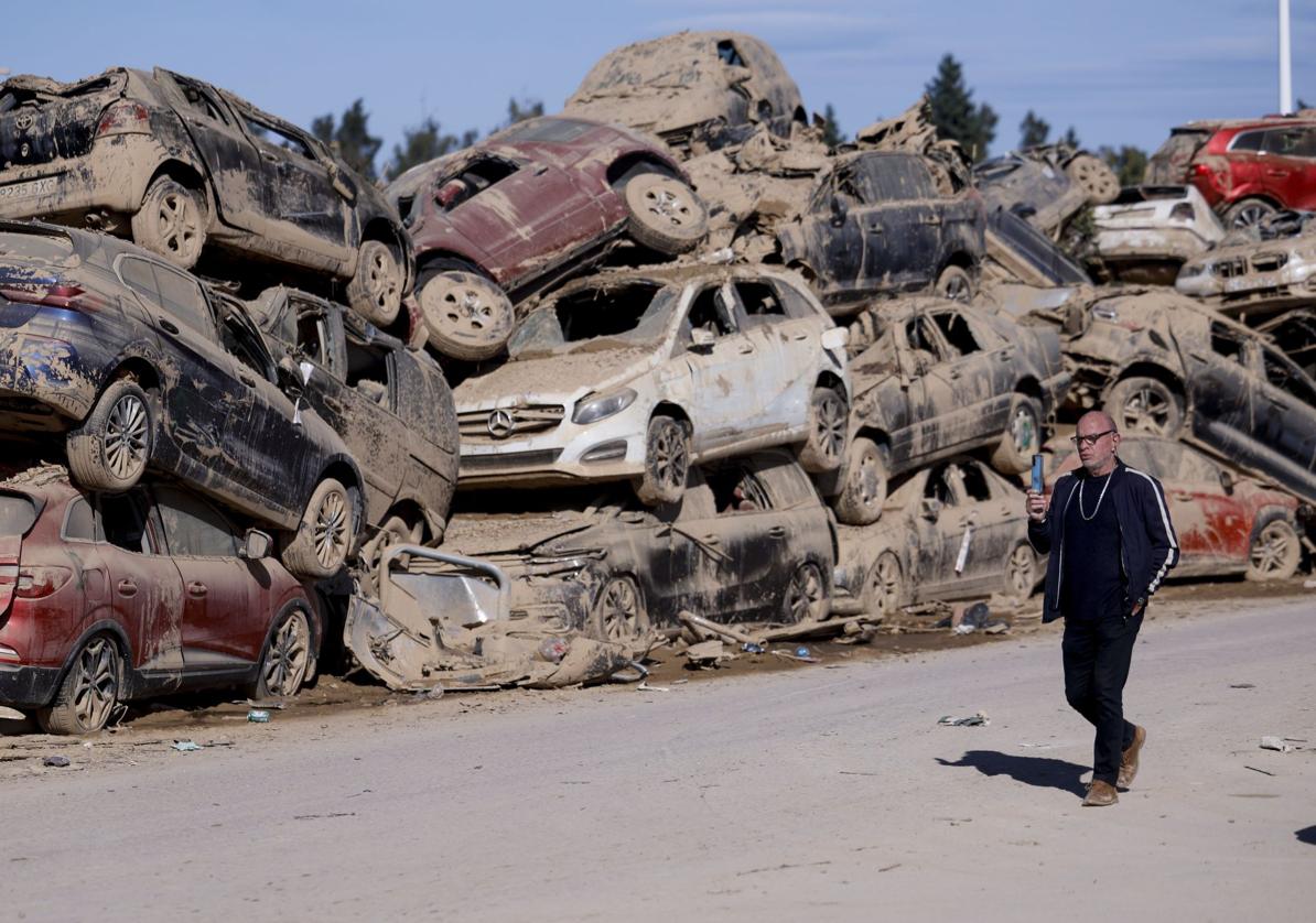 Un hombre pasa ante los innumerables coches apilados en Catarroja, tres semanas después de la DANA.