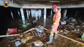 Un bombero, en un garaja arrasado por el barro y los enseres arrastrados por la riada.