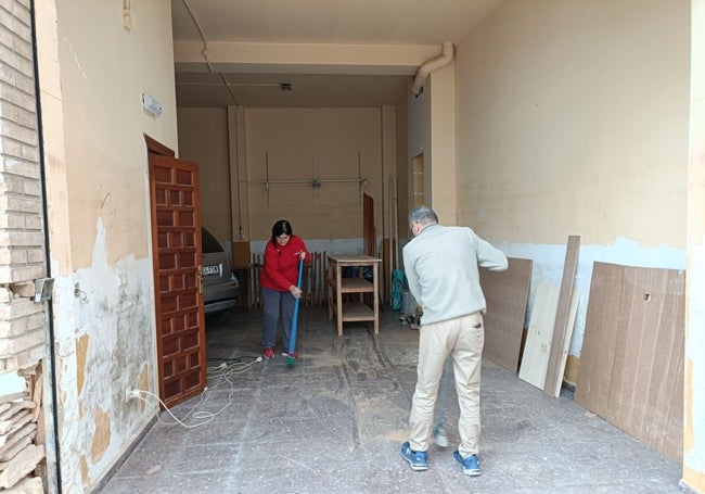 Vicenta y Rafa barren la planta baja de su casa.