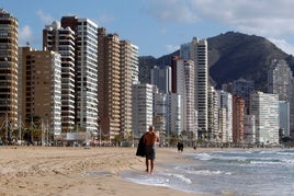 Una persona pasea por la playa de Benidorm. Imagen de archivo.