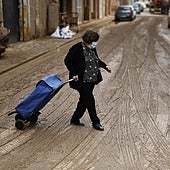 Una mujer intenta no resbalar entre el lodazal que se han vuelto a convertir las calles en Massanassa