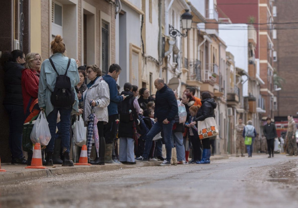 Vecinos en una calle embarrada afectada por la DANA.