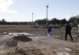 Dos personas caminan por el campo de fútbol de Alfafar, destruido.