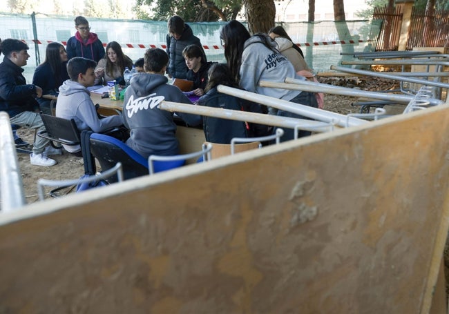 Los alumnos han simulado dar una clase en los pupitres y sillas llenos de barro que se apilan en los exteriores del instituto.