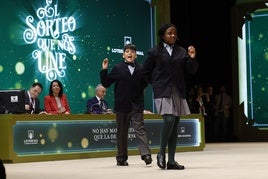 Dos niños de San Idelfonso en el sorteo de 2023 y, tras ellos, los miembros de la mesa.