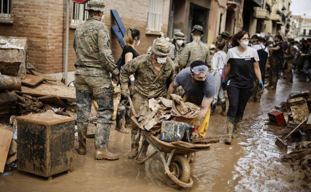 Varios militares y voluntarios limpian fango, en la foto elegida por el Rey.