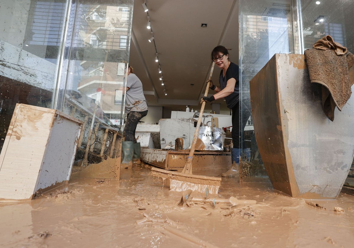 Propietaria de un pequeño comercio limpia su local, arrasado por las inundaciones.