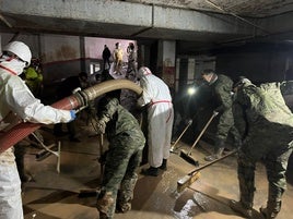 Militares trabajando este martes en un garaje aún tomado por el agua y el lodo en Catarroja.