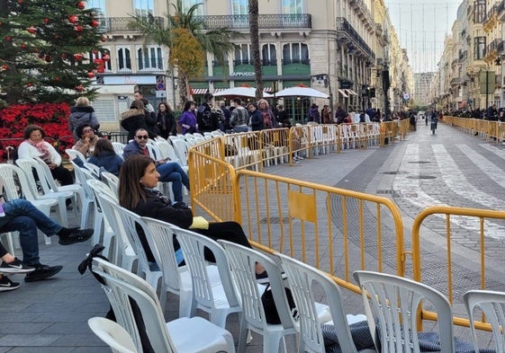 Varias personas sentadas en las sillas en la plaza de la Reina de Valencia.