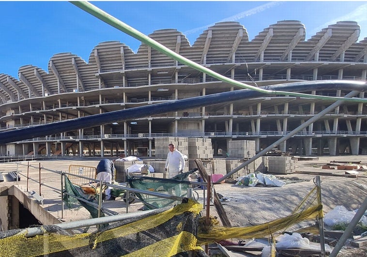 Dos trabajadores apilan sacos de cemento en una de las entradas de la obra del nuevo Mestalla.