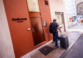 Un turista con su maleta, ante la puerta de un bloque de pisos turísticos en Valencia.