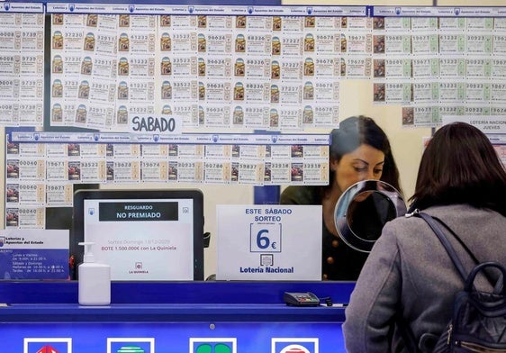 Una mujer compra un décimo en una administración de Lotería.