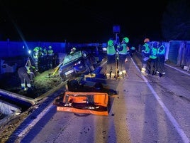 Policías y bomberos, junto al coche en el que viajaban los dos ancianos fallecidos en el siniestro.