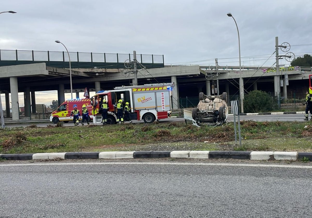 Los bomberos, en el escenario del accidente junto al vehículo volcado.