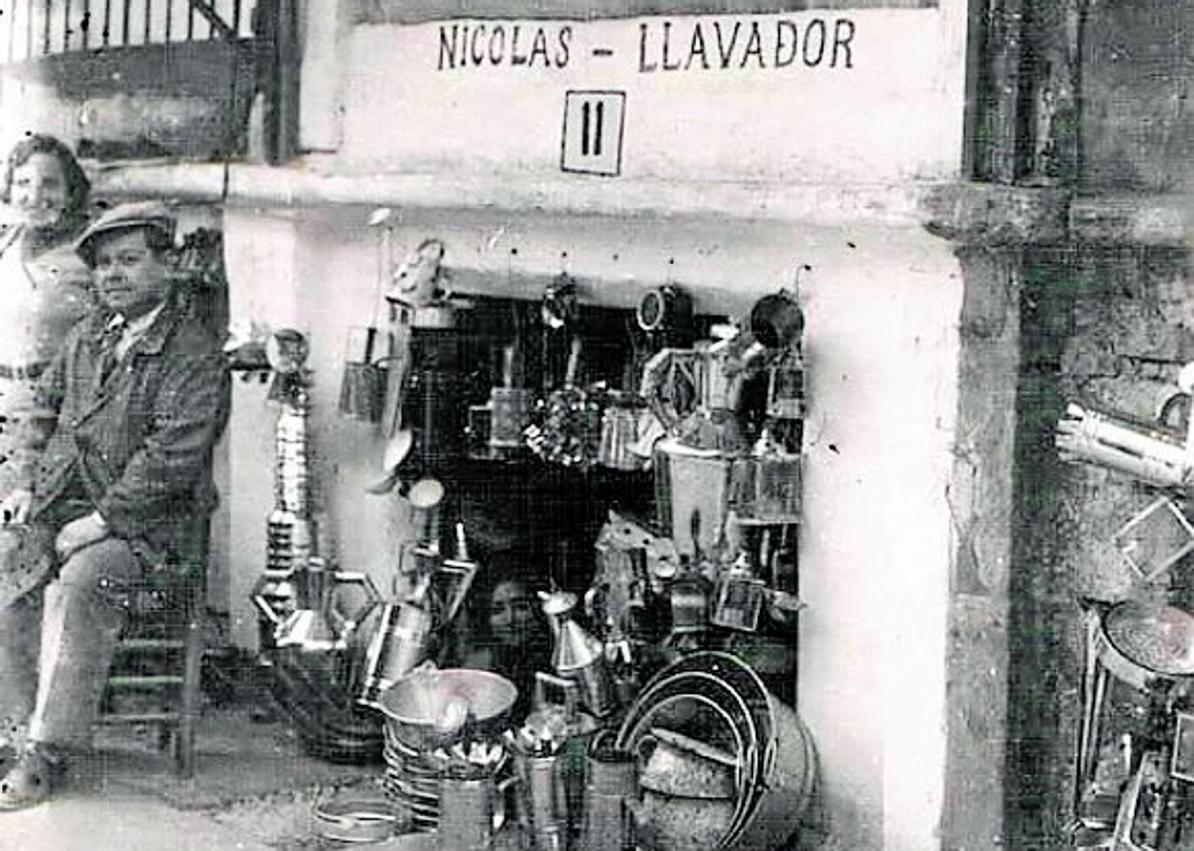 Imagen secundaria 1 - Año 1925. Tres mujeres sentadas junto a uno de los locales dedicados a alpargatería. | El número 11. El puesto de Nicolás Llavador, donde se acumulan productos para uso doméstico. | Cubos y pozales. Fotografía tomada en los años cincuenta donde se aprecian multitud de artilugios y enseres para la limpieza y las tareas de la casa. 