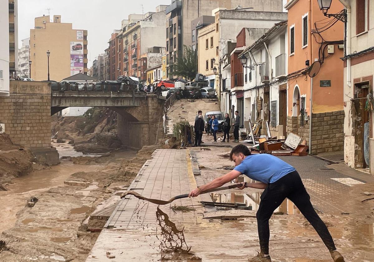 Un joven quita barro en Chiva a la mañana siguiente de la dana.