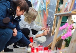 Dos mujeres colocan velas y fotos de las víctimas en el Puente de la Solidaridad.