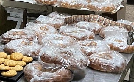 Imagen secundaria 1 - Arriba, panellet con el sello de Sant Blai. Sobre estas líneas, el párroco benficiendo los rotllos en uno de los hornos de la localidad.