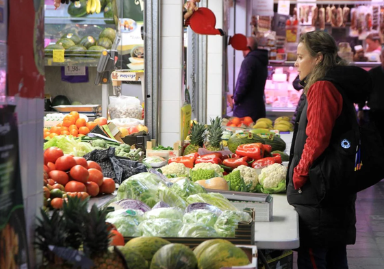 Una mujer realizando la compra de verduras en un mercado local, imagen de archivo.