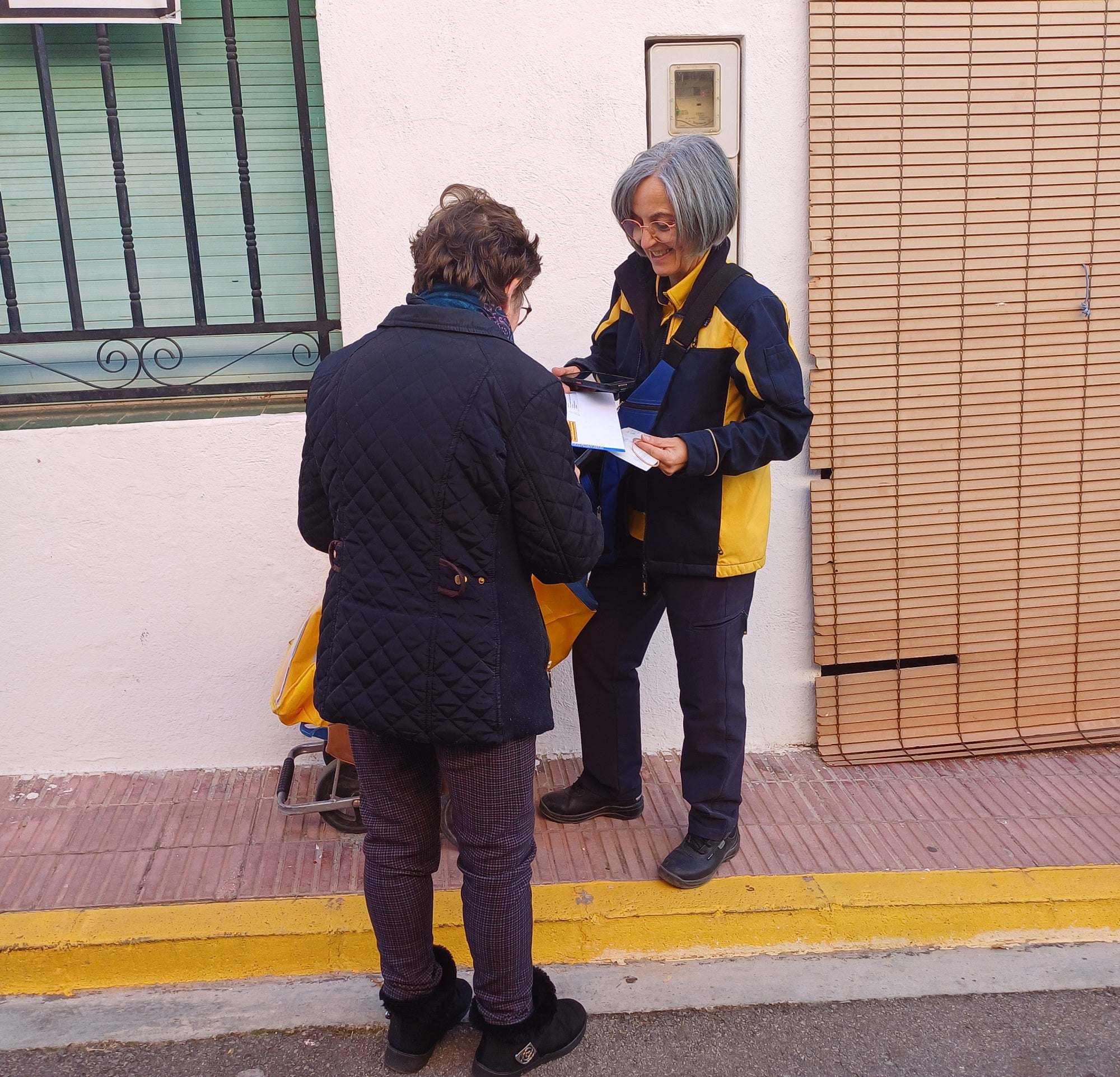 Mª Carmen Climent entrega una notificación a una vecina.