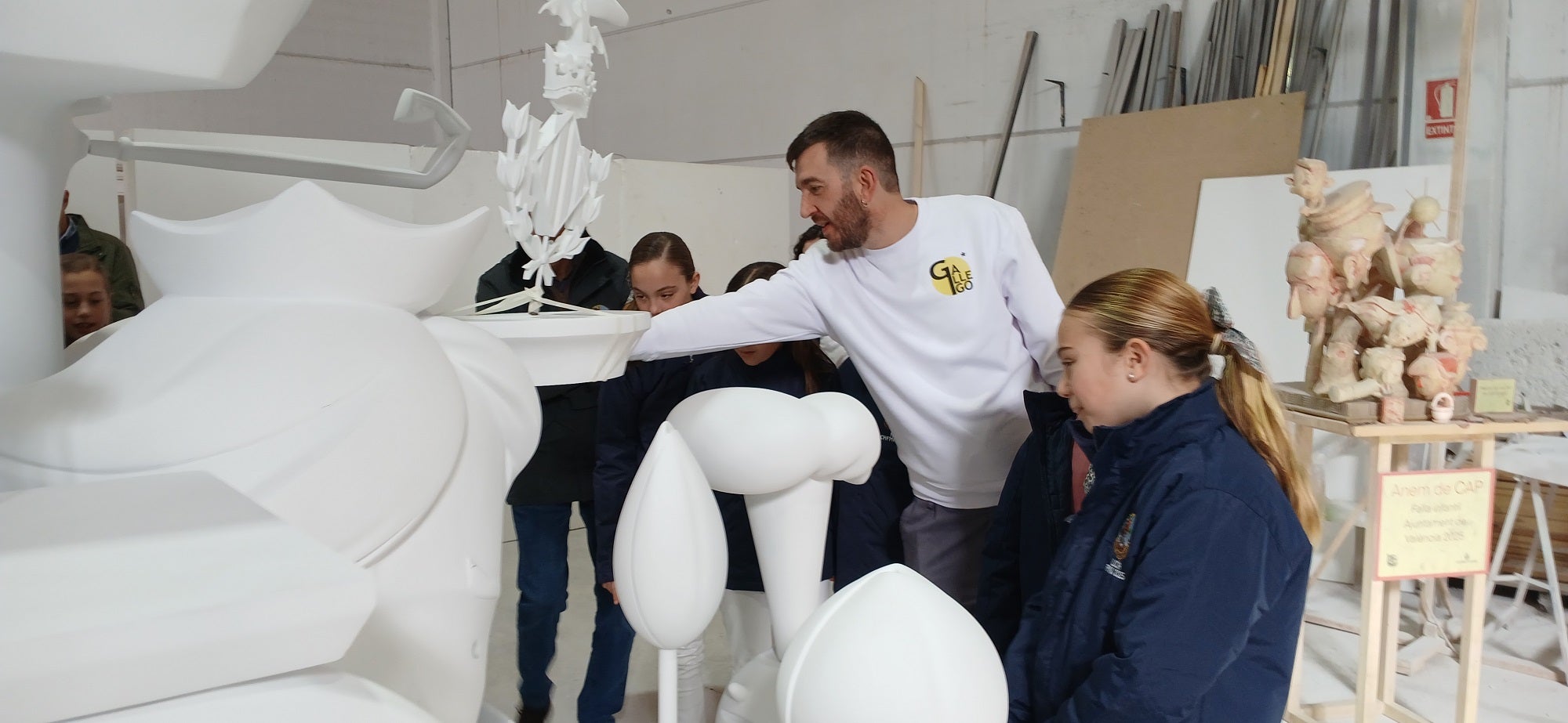 Imagen secundaria 2 - Arriba, el monumento fallero sin pintar. Sobre estas líneas, la fallera mayor infantil y las niñas que conforman la corte de honor, pendientes de las explicaciones del artista José Gallego.