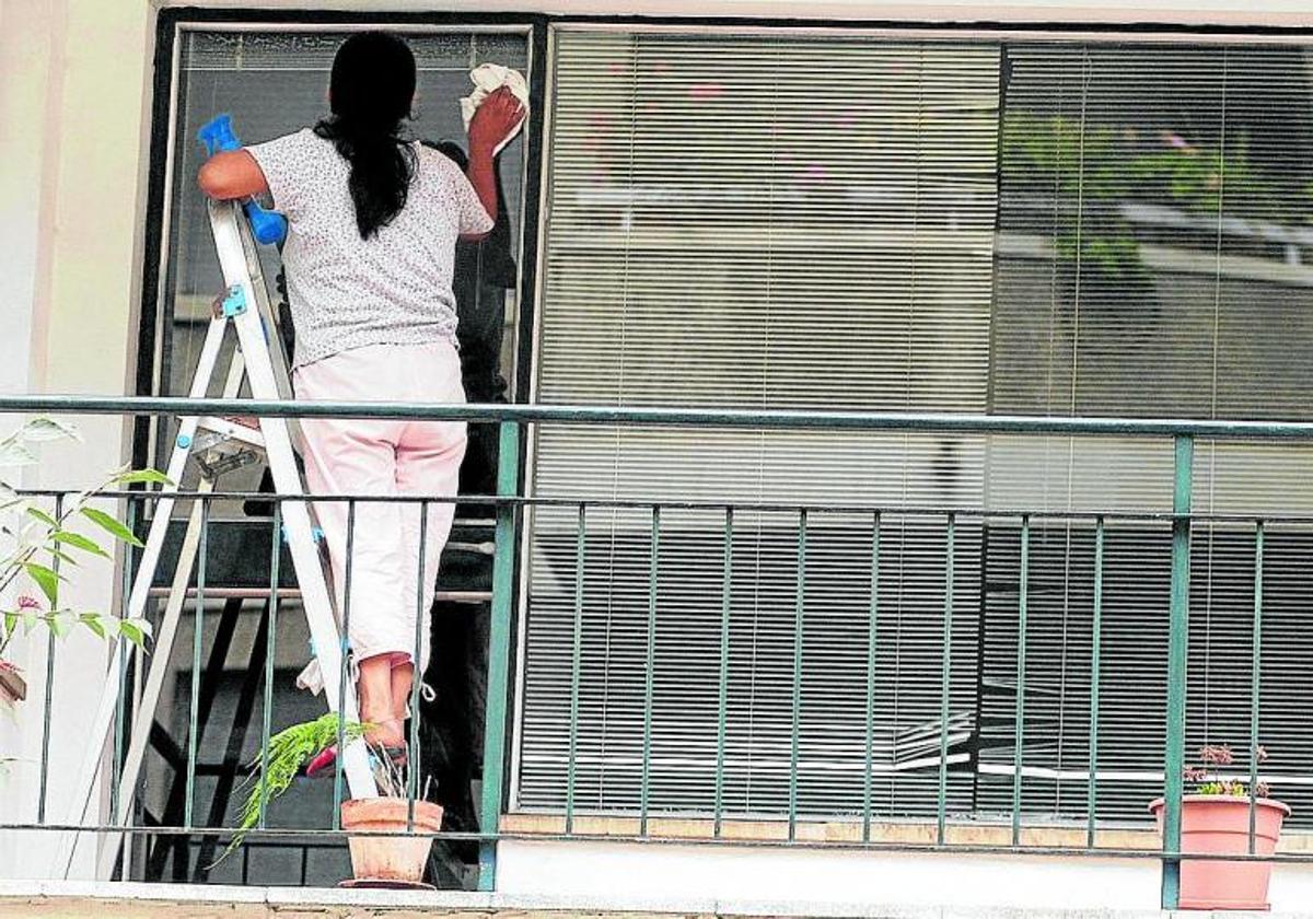 Una empleada de hogar limpia los cristales de una vivienda, en una imagen de archivo.