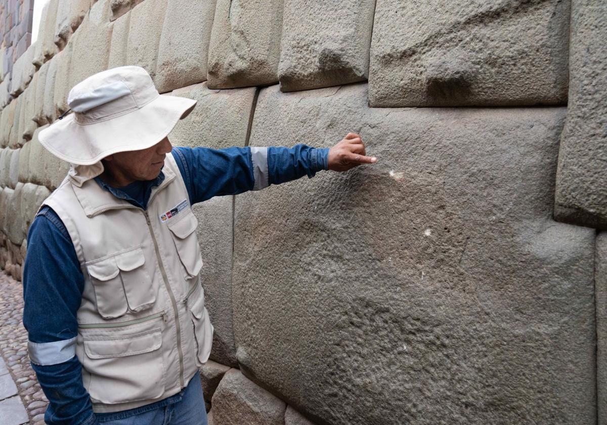 Un funcionario del Ministerio de Cultura de Perú señala daños en la 'piedra de los 12 ángulos'.