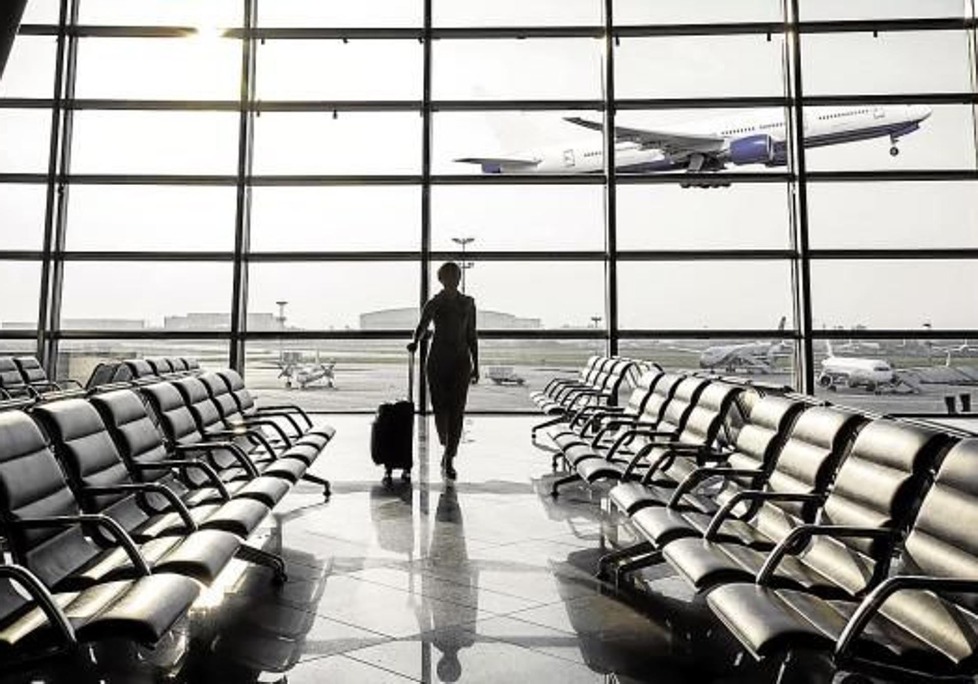 Una mujer con su maleta espera la llegada de un vuelo