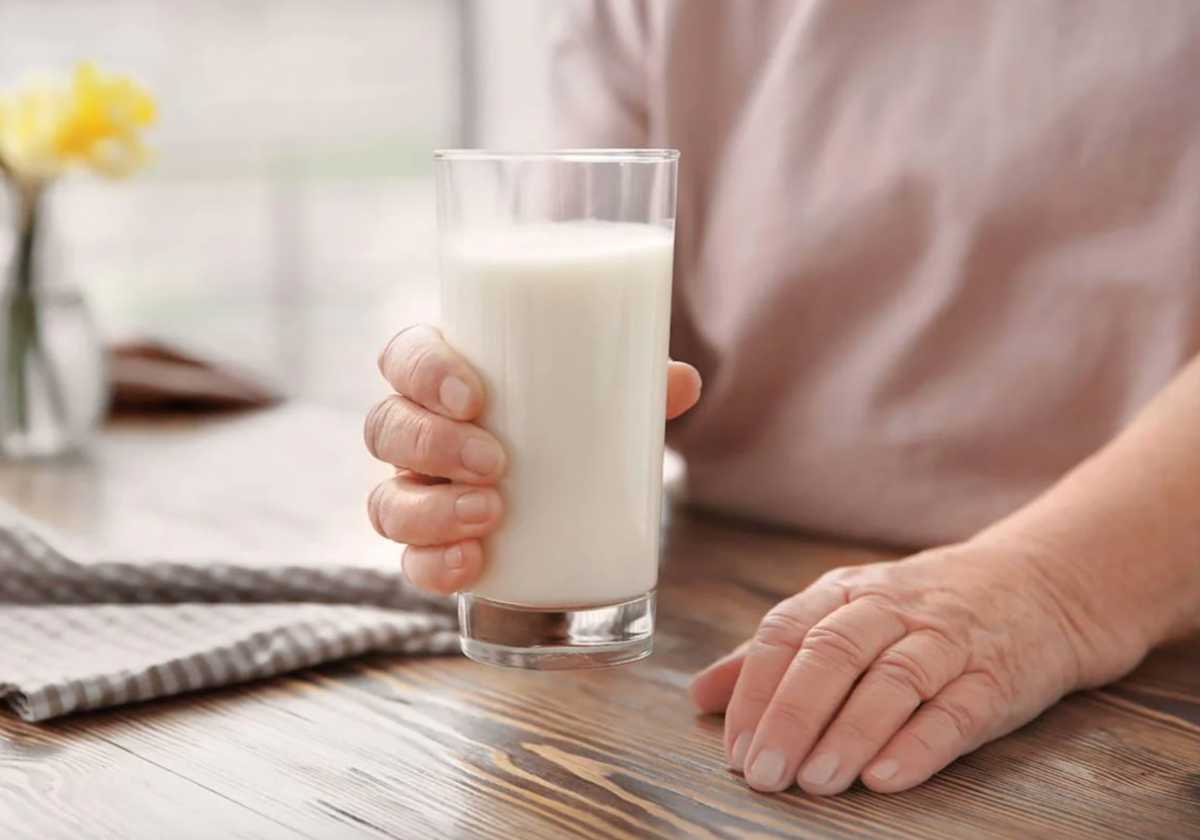 Una mujer sostiene un vaso de leche.