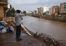 Un hombre observa la crecida del barranco del Poyo en Paiporta.